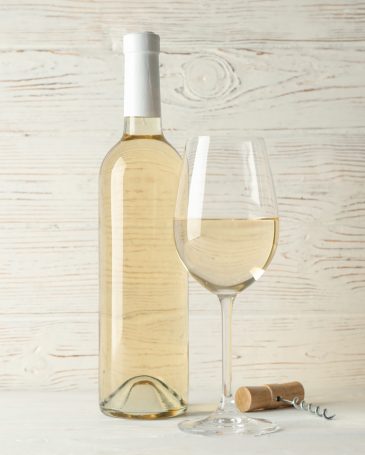 Corkscrew, bottle and glass with wine on white wooden background, copy space