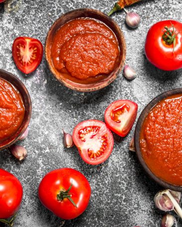 Tomato sauce with spices and herbs. On rustic background.